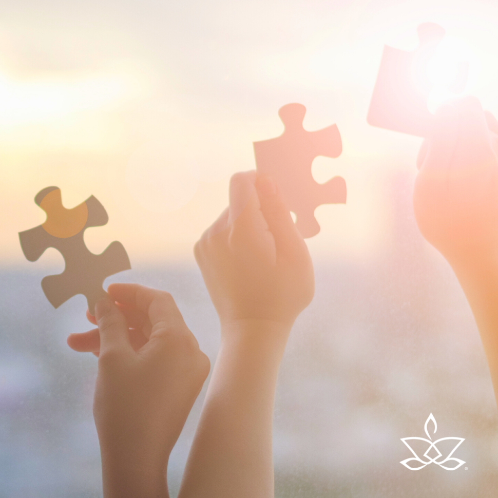 Ruce skládající k sobě dílky puzzle proti svítání